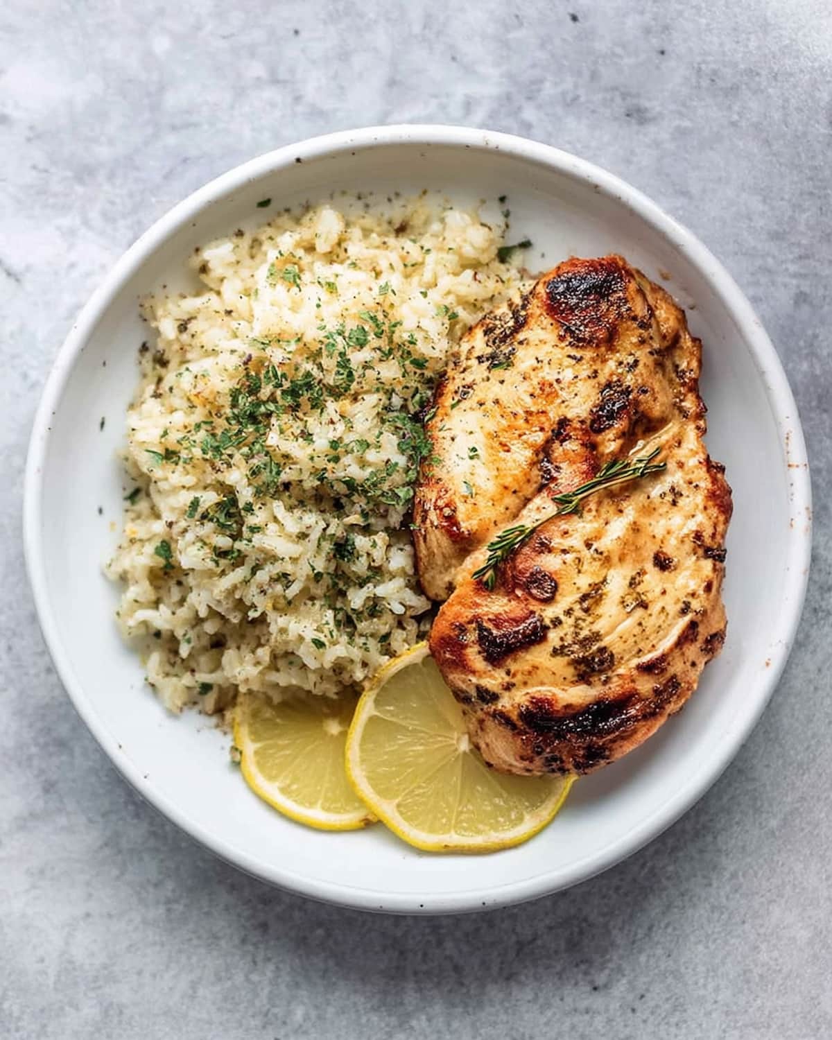 Instant Pot chicken breast and rice, served with fresh herbs and lemon slices.