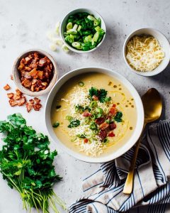 Instant Pot potato cauliflower soup, topped with crispy bacon, shredded cheese, green onions.