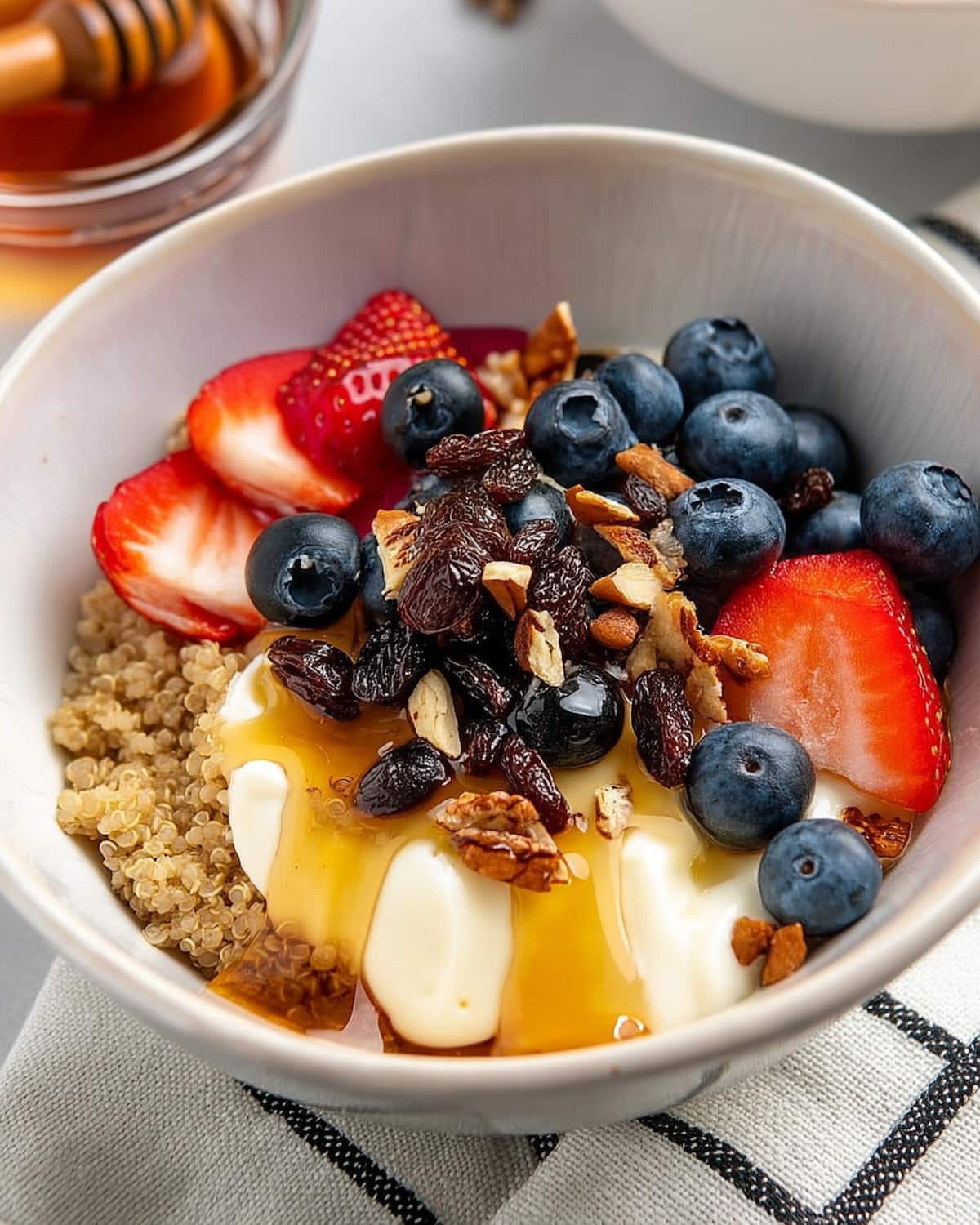 Instant Pot quinoa breakfast bowl topped with yogurt, fresh berries, raisins, nuts.