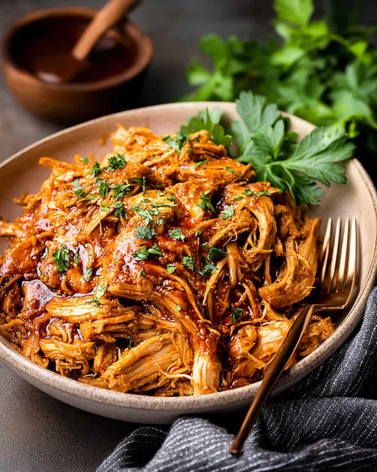 Instant Pot BBQ chicken coated in smoky sauce, topped with fresh parsley.
