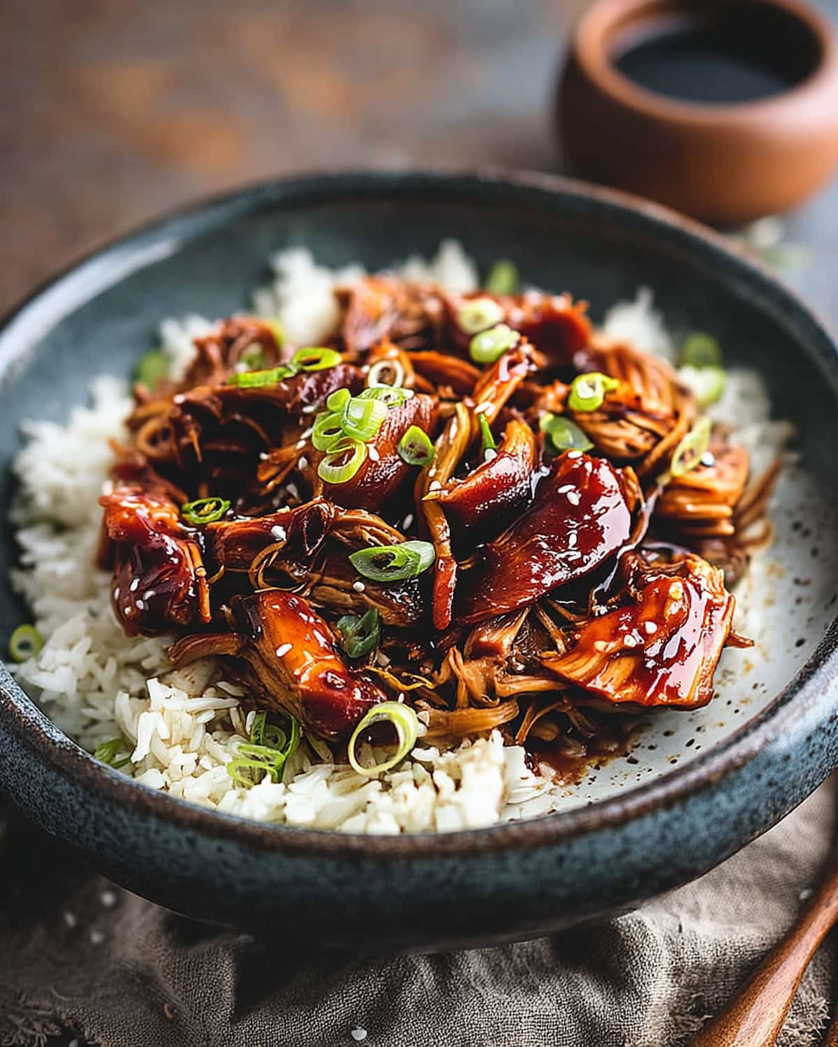 Instant Pot teriyaki chicken served over fluffy white rice, topped with sliced green onions and coated.