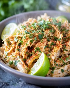 Instant Pot shredded chicken salad with tender seasoned chicken, fresh cilantro, and lime wedges.